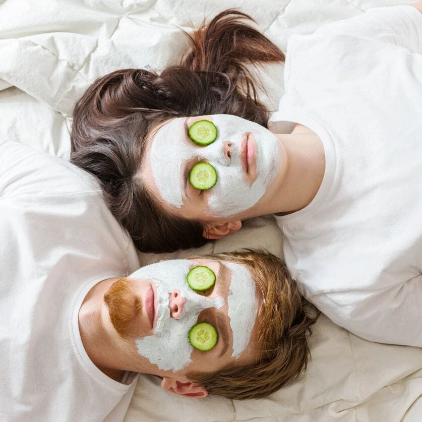 Couple wearing facial masks with cucumber slices